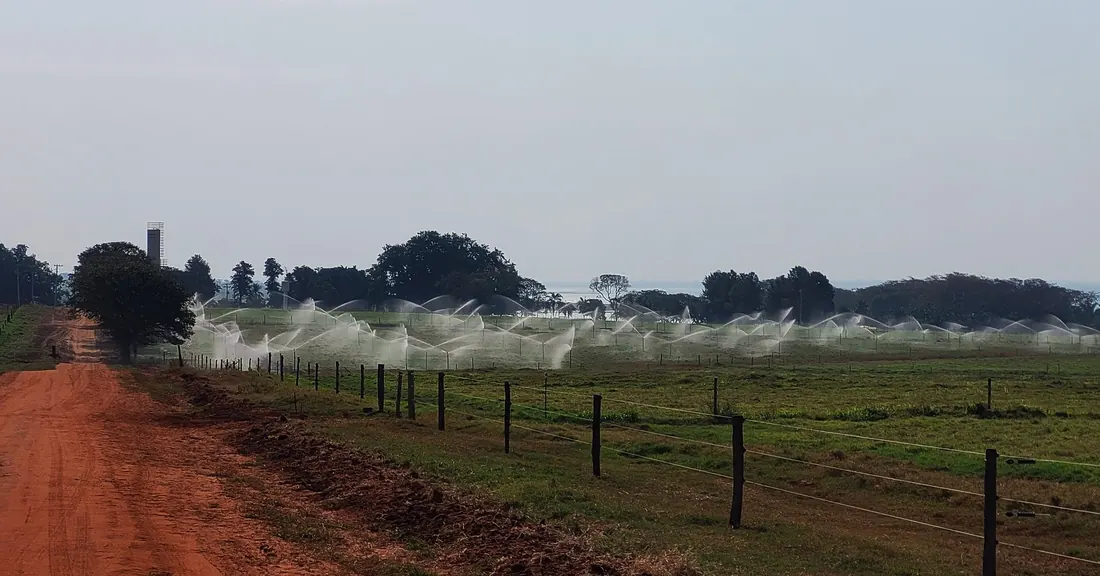 Aspersores ligados num pasto ao lado de uma estrada de terra